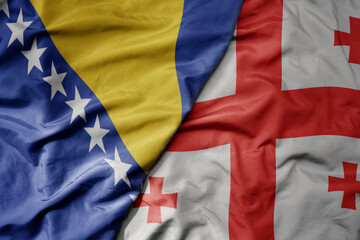 big waving national colorful flag of bosnia and herzegovina and national flag of georgia .