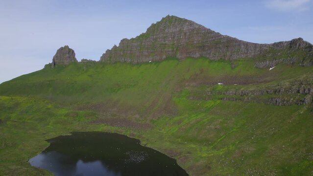 Drone rising above lake  with extreme landscape in background in the remote wilderness of Hornstradir, Iceland.