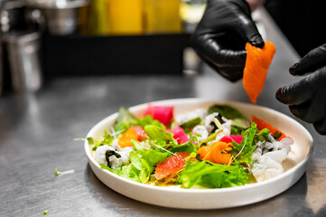 chef hands cooking Fresh sashimi salad with salmon fish, tuna and vegetables on kitchen