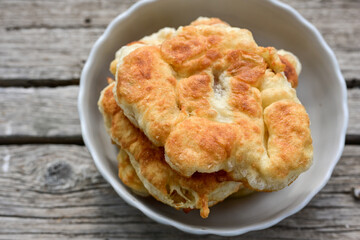 Traditional Bulgarian home made deep fried  patties  covered with sugar  оn rustic backgroud.Mekitsa or Mekica,  on wooden  rustic  background. Made of kneaded dough that is deep fried 