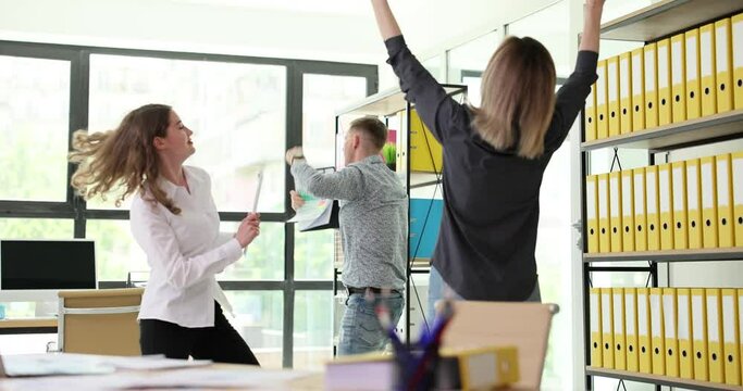 Formally dressed young coworkers dancing in modern office. Cheerful team man and women celebrating success of joint start-up project slow motion