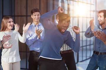 Overjoyed diverse businesspeople triumph have fun dancing in modern office corridor,