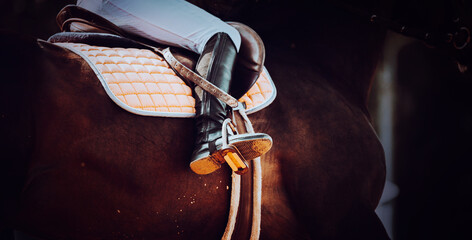 A close-up of the rider's boots as he gallops on his chestnut horse. The equestrian sport and the...
