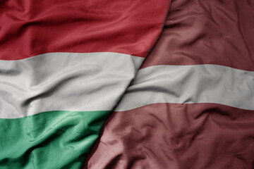 big waving national colorful flag of hungary and national flag of latvia .