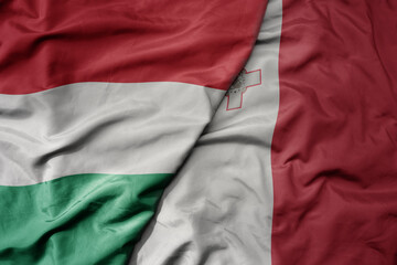 big waving national colorful flag of hungary and national flag of malta .