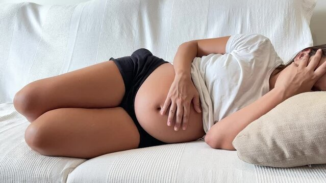 Pregnant woman lying on the sofa stroking her tummy. Concept of pregnancy and bad being