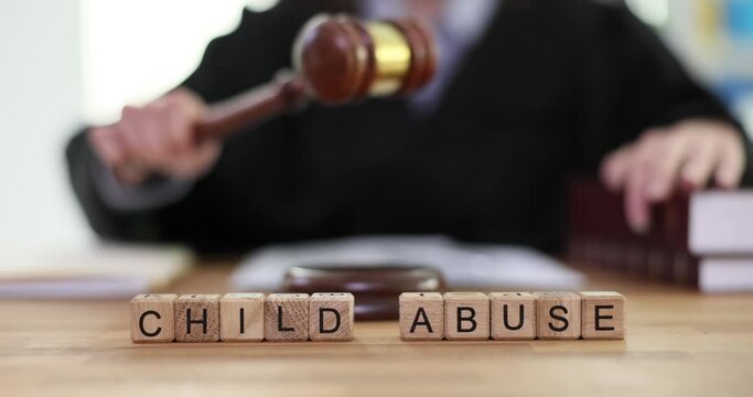 Phrase Child Abuse made of wooden blocks against woman judge in work uniform knocking with gavel. Maltreatment and neglect of child by parents slow motion