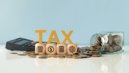 Word tax and Tax icons on wooden block with glass coin jar and  calculator place on table for...