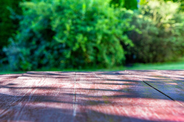 Drewniany stół na tle rozmytej zieleni w ogrodzie. Tło