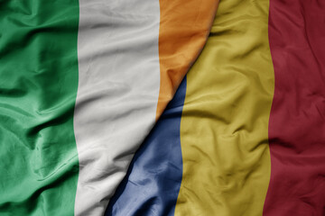 big waving national colorful flag of ireland and national flag of romania .