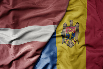 big waving national colorful flag of latvia and national flag of moldova .