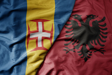 big waving national colorful flag of madeira and national flag of albania .