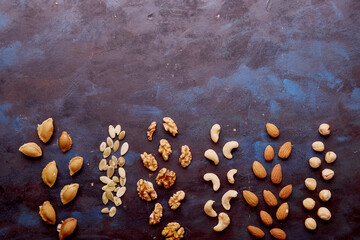 Aesthetics food snacks rustic background with assorted nuts. Hazelnuts , walnuts, almonds, cashews, apricot pit. Copy space