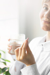 A woman holds a pill in her hand. Taking medications, vitamins.