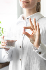 A woman holds a pill in her hand. Taking medications, vitamins.