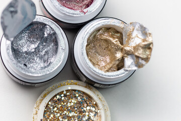 This photo shows a collection of glitter gel nail polishes in small jars. Vibrant colors and sparkling glitter create an eye-catching nail look.