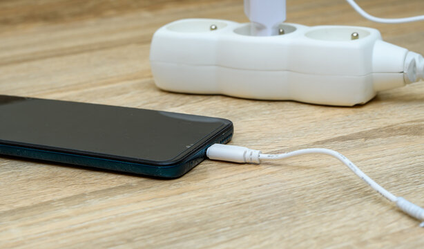 Ładowanie telefonu kom&oacute;rkowego kablem podpiętym do prądu 