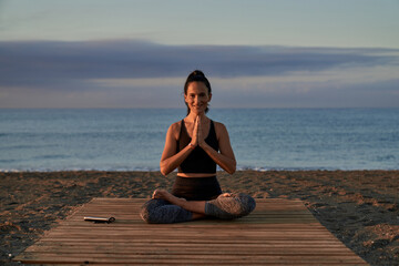 Fototapeta na wymiar Positive Hispanic woman meditating on shore