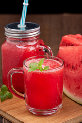 Close up of ripe watermelon smoothie in glass mug and jar.