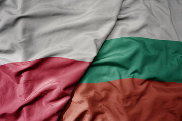 big waving national colorful flag of poland and national flag of bulgaria .