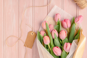 Pink tulip flowers bouquet on pale pink wooden background. Flat lay, top view. Spring floral concept.