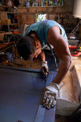 Unrecognizable man measuring metal sheet in workshop
