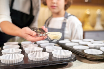 Anonymous mother with cupcake batter near son