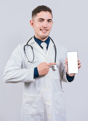 Cheerful doctor holding and pointing at cell phone screen. Young doctor showing and pointing at smatphone screen isolated