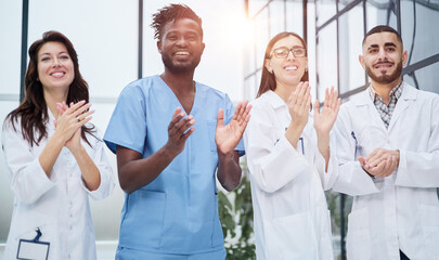 Successful team of different doctors clapping hands