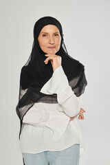 portrait of woman in hijab looking at camera and posing isolated on grey