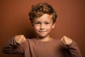Medium shot portrait photography of a satisfied kid male making a i'm strong gesture showing muscles against a copper brown background. With generative AI technology