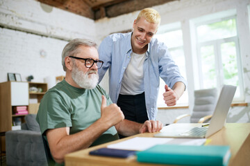 Cooperation of adults and youngsters. Young man helping senior businessman with technological issues on laptop. Concept of business, age diversity, education, modernity, innovations, assistance