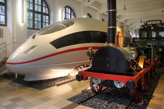 Nuremberg, Germany - August 26, 2023: First German steam engine Adler of 1835 and modern ICE train at the Deutsche Bahn Railway Museum in Nuremberg