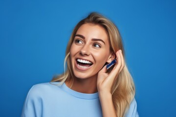 Fototapeta premium Close-up portrait photography of a joyful girl in her 30s making a telephone call gesture with the hand against a periwinkle blue background. With generative AI technology