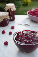 Raspberry jam with berry on a light background. Banner, menu, recipe. Side view.