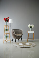 gray wall interior decoration with rattan chair and rug beside decorated bedside table and bed lamp