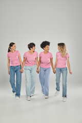 Fototapeta premium breast cancer awareness, positive multicultural women with pink ribbons walking together on grey