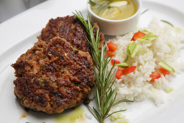 Fried meatballs served with white rice and rosemary on the restaurant table	