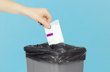 Throw women's pads into the trash can, women's pads in hand in front of the trash can. Disposal of...