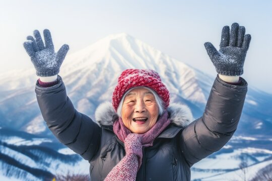 Headshot portrait photography of a cheerful old woman holding hands up in surrender dressed in a warm ski hat near the mount fuji in honshu island japan. With generative AI technology