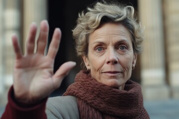 Close-up portrait photography of a jovial mature woman waving hello or goodbye dressed in a classic turtleneck at the uffizi gallery in florence italy. With generative AI technology