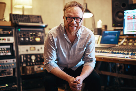 Music producer smiling while sitting in his recording studio