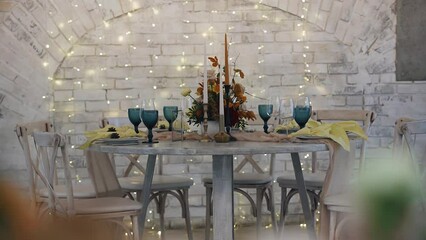 The festive table is set for several people. The table is decorated with candles and various decor