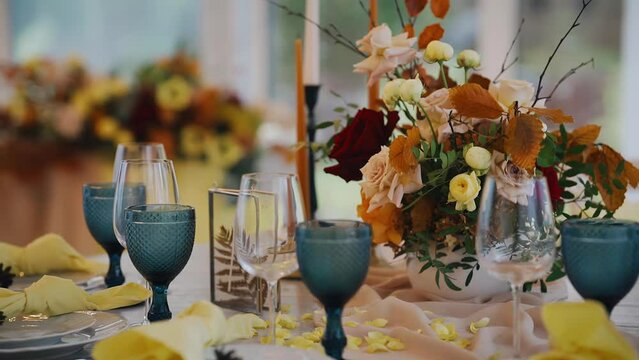 There are glasses and candles on the festive table, as well as a beautiful decor. Smooth camera movement