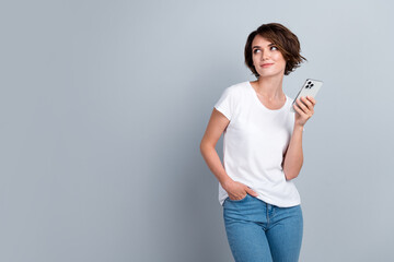 Photo of pretty minded creative person hold apple iphone gadget look empty space isolated on grey...