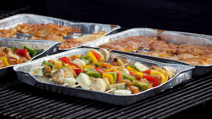 vegetables on a skewer and chicken meat in spices are laid out on gray grill plates. B-B-Q. outdoor cooking