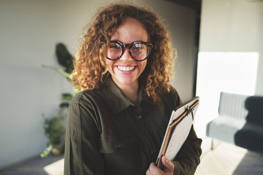 Young businesswoman standing in an office hallway and laughing - Powered by Adobe