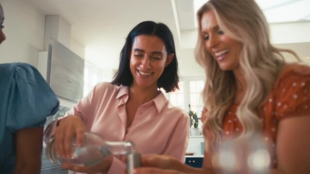 Three mature female friends at home having fun mixing and drinking cocktails together - shot in slow motion