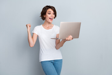 Portrait of overjoyed ecstatic woman wear stylish t-shirt look at laptop shouting yeah win betting...