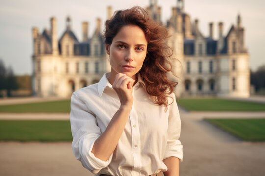 Photography in the style of pensive portraiture of a glad girl in her 30s making a fist wearing a classic white shirt at the chateau de chambord in chambord france. With generative AI technology